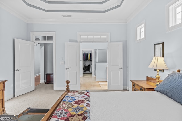 carpeted bedroom with a closet, a tray ceiling, and ornamental molding