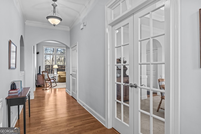 hallway with hardwood / wood-style floors, ornamental molding, and french doors