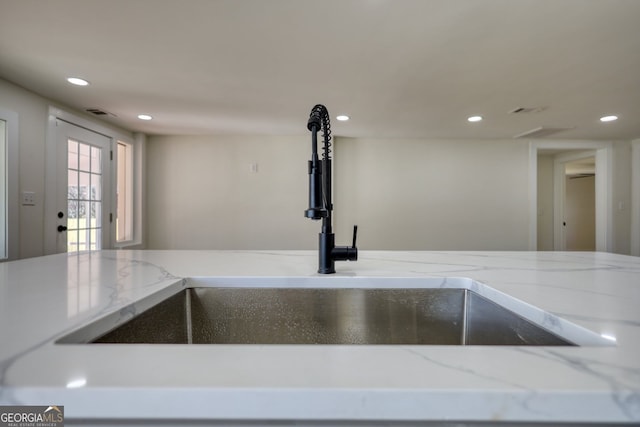 room details with recessed lighting, light stone countertops, and a sink