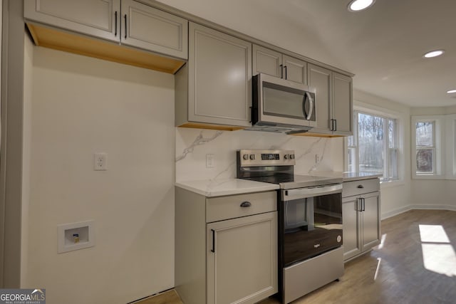 kitchen featuring recessed lighting, gray cabinets, stainless steel appliances, decorative backsplash, and light wood-style floors