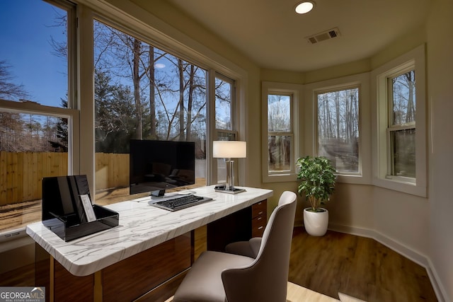 home office featuring visible vents, a healthy amount of sunlight, baseboards, and wood finished floors