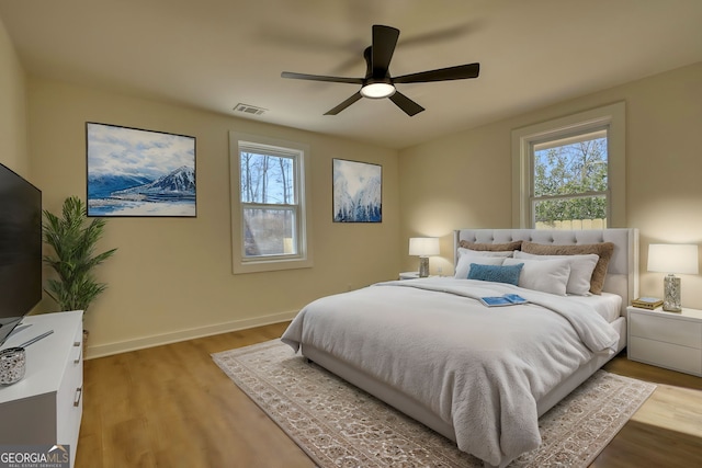 bedroom featuring multiple windows, wood finished floors, visible vents, and baseboards