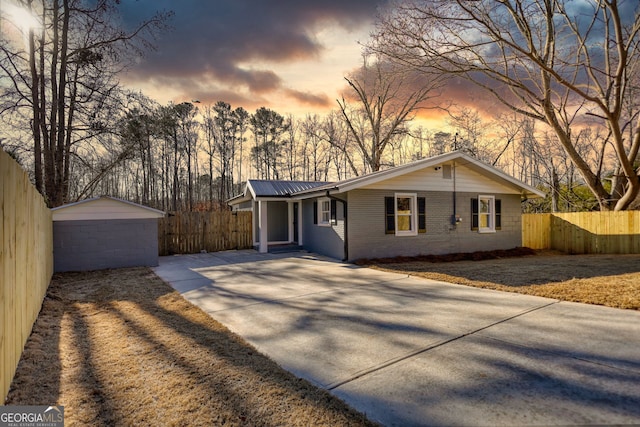 ranch-style house with an outbuilding, driveway, metal roof, and fence