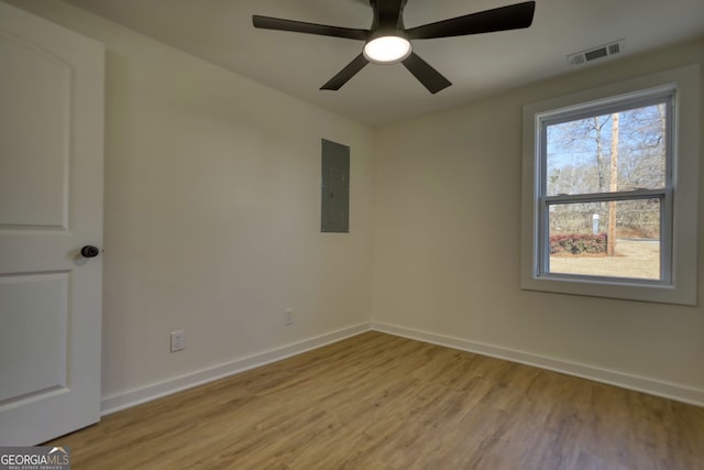 empty room with baseboards, visible vents, electric panel, ceiling fan, and light wood-type flooring