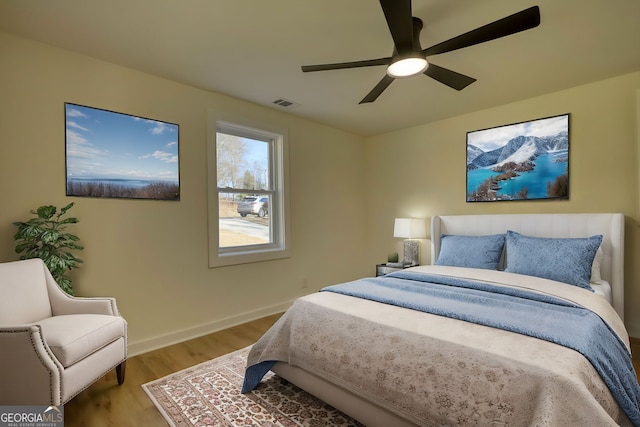 bedroom with visible vents, light wood-style flooring, a ceiling fan, and baseboards