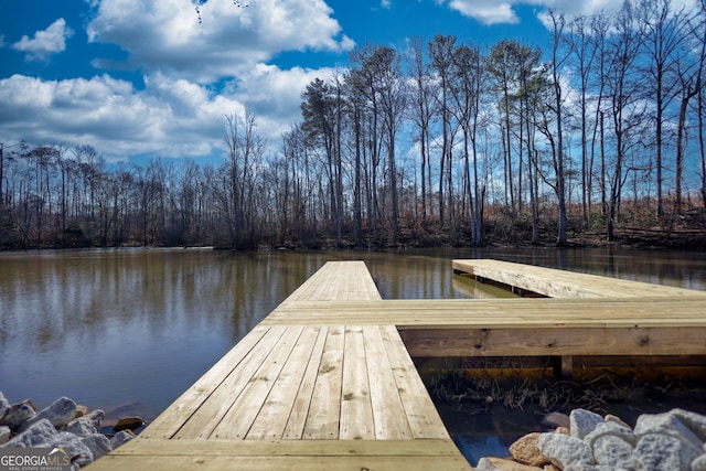 dock area featuring a wooded view and a water view