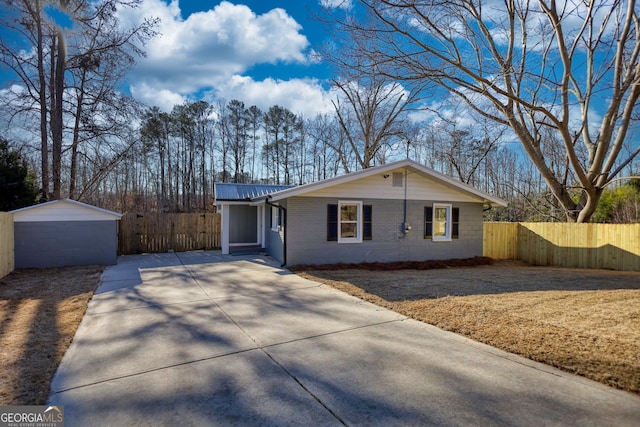 ranch-style house featuring metal roof, concrete block siding, an outdoor structure, and fence