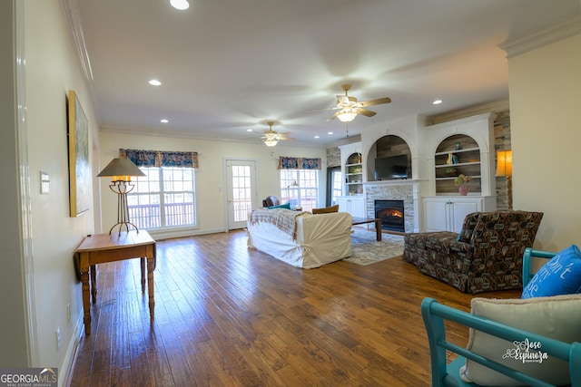 living room with hardwood / wood-style flooring, a fireplace, ornamental molding, and built in shelves