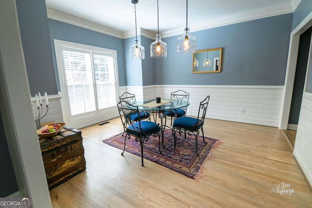 dining space featuring light wood-type flooring and ornamental molding