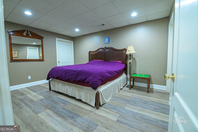 bedroom featuring a paneled ceiling and light hardwood / wood-style floors