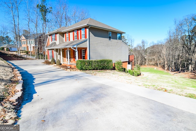 view of side of property with covered porch and a lawn