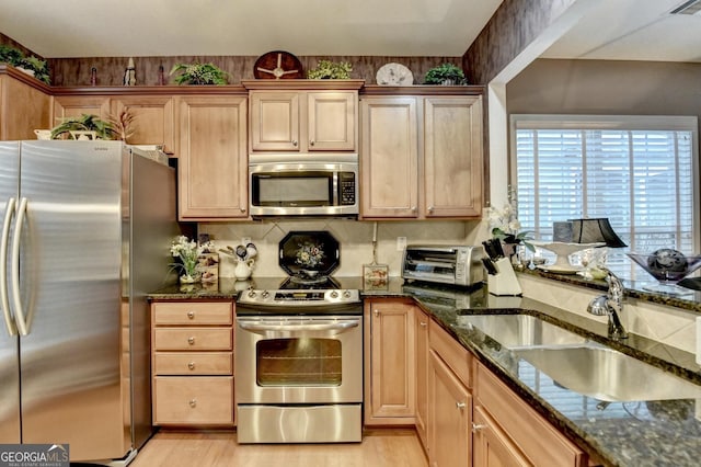 kitchen featuring light hardwood / wood-style floors, sink, appliances with stainless steel finishes, and dark stone counters