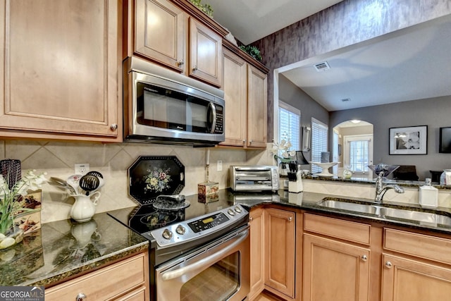 kitchen with sink, decorative backsplash, dark stone countertops, and appliances with stainless steel finishes