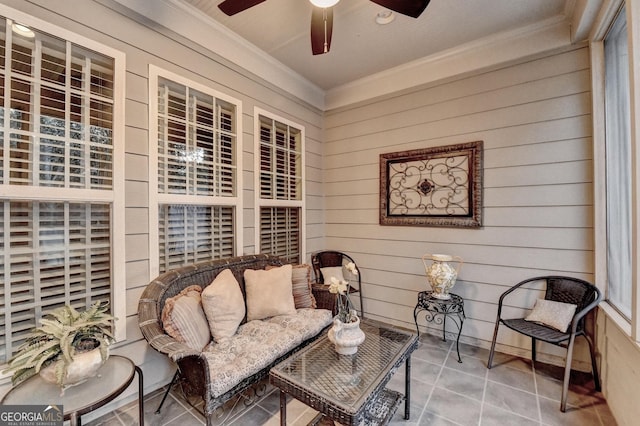 living area featuring ceiling fan, wood walls, tile patterned floors, and crown molding