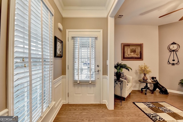 doorway with light wood-type flooring, ceiling fan, and ornamental molding