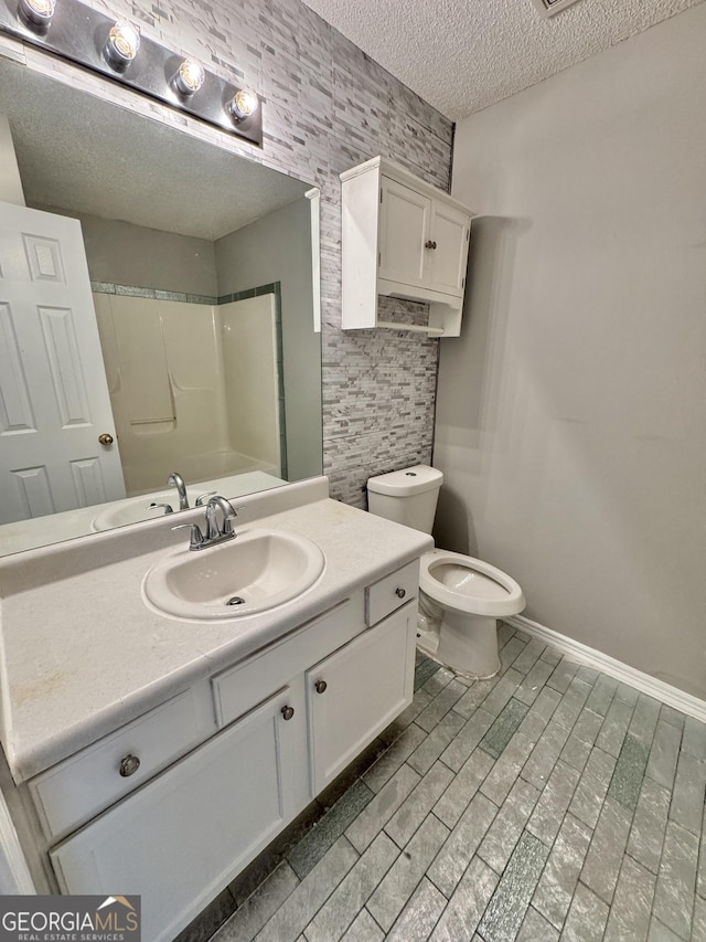 full bathroom with washtub / shower combination, a textured ceiling, toilet, and vanity