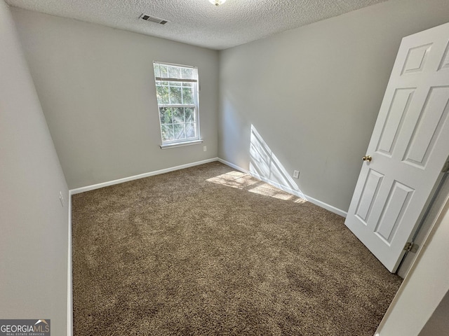 unfurnished room featuring a textured ceiling and dark carpet