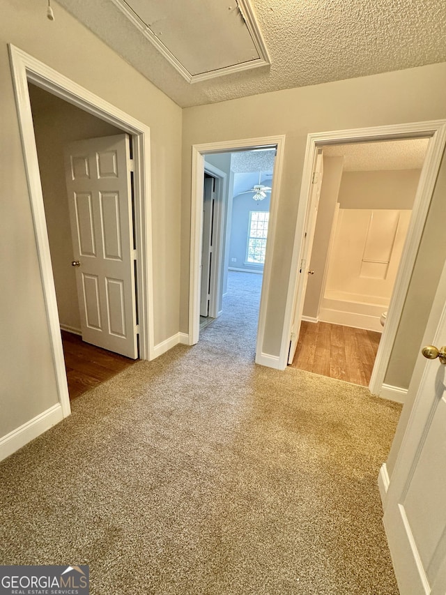 hall featuring a textured ceiling and carpet floors