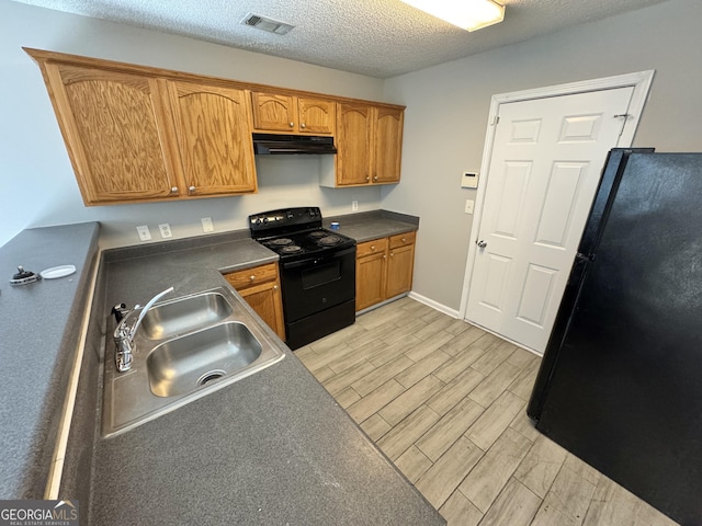 kitchen featuring black appliances, a textured ceiling, and sink