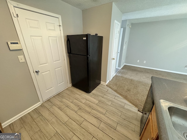 kitchen with black refrigerator, a textured ceiling, and sink