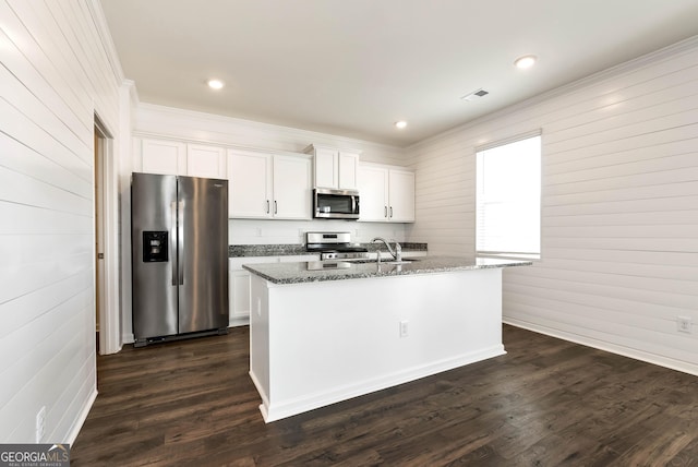 kitchen with a center island with sink, white cabinets, dark stone countertops, and appliances with stainless steel finishes