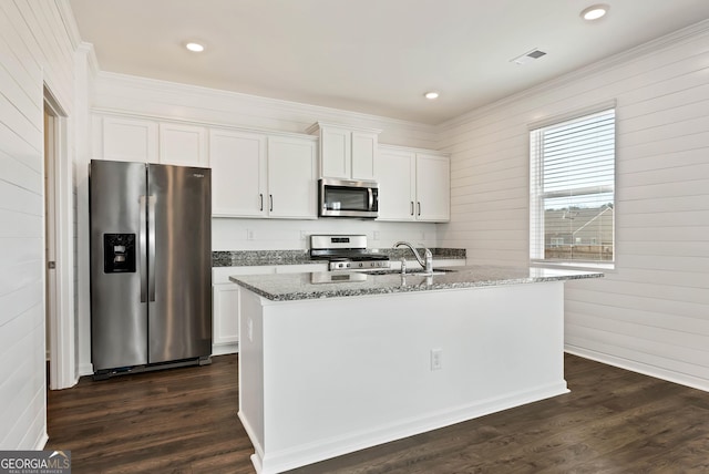 kitchen with dark wood-type flooring, white cabinetry, stainless steel appliances, an island with sink, and stone countertops