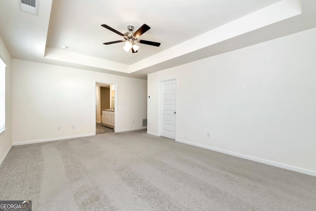 carpeted empty room featuring ceiling fan and a tray ceiling