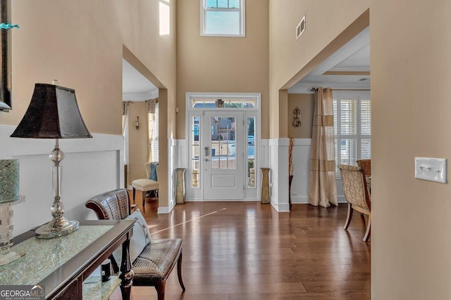 entryway featuring dark wood-type flooring, a wealth of natural light, and ornamental molding