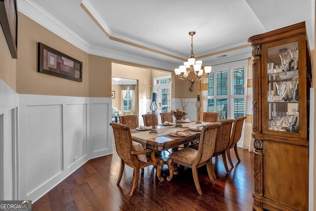 dining area featuring crown molding, dark wood-type flooring, a chandelier, and a tray ceiling