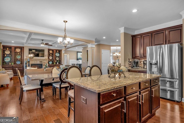 kitchen with stainless steel fridge, a breakfast bar area, beam ceiling, a center island, and coffered ceiling