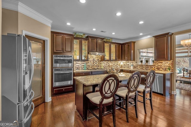 kitchen featuring crown molding, stainless steel appliances, a breakfast bar area, and a kitchen island