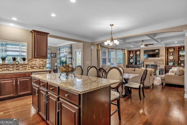 kitchen with a breakfast bar area, a center island, coffered ceiling, decorative light fixtures, and beamed ceiling