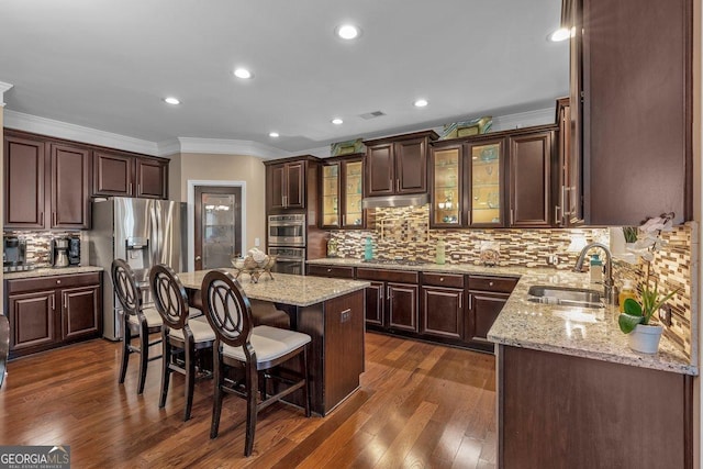 kitchen with sink, a breakfast bar area, dark hardwood / wood-style floors, a kitchen island, and stainless steel appliances