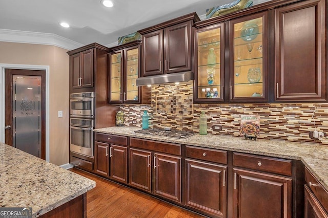 kitchen featuring dark brown cabinetry, light stone countertops, ornamental molding, and appliances with stainless steel finishes