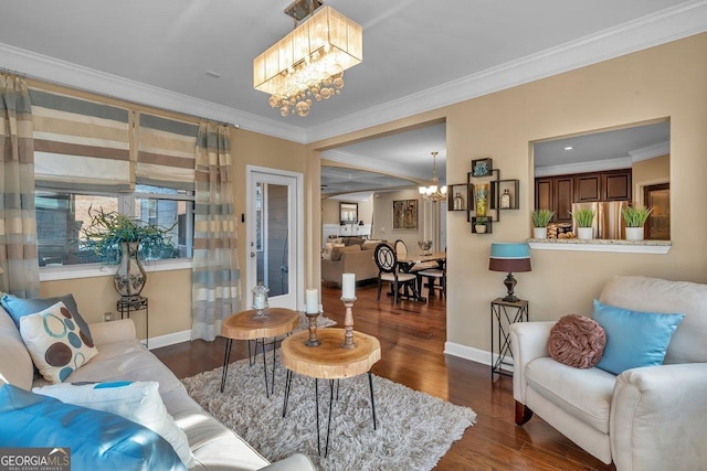 living room with dark wood-type flooring, ornamental molding, and a chandelier