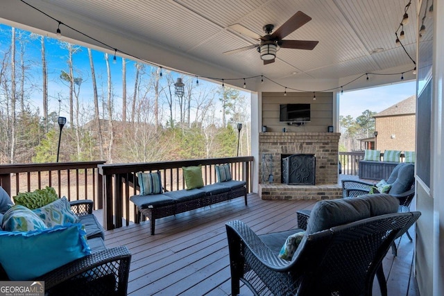 wooden terrace with an outdoor living space with a fireplace and ceiling fan