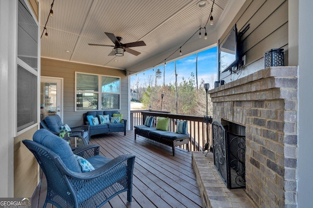 wooden terrace with an outdoor living space with a fireplace and ceiling fan