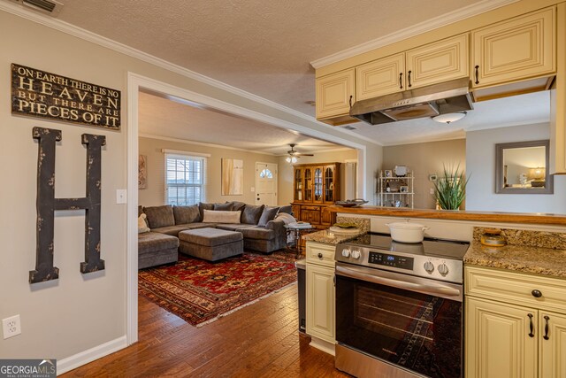 kitchen featuring a textured ceiling, dark wood-type flooring, stainless steel range with electric stovetop, crown molding, and cream cabinetry
