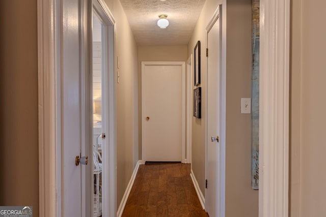 hall with dark wood-type flooring and a textured ceiling