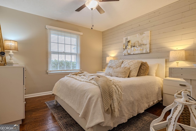 bedroom with dark wood-type flooring, wooden walls, and ceiling fan
