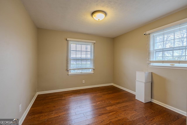 spare room with dark hardwood / wood-style floors and a textured ceiling