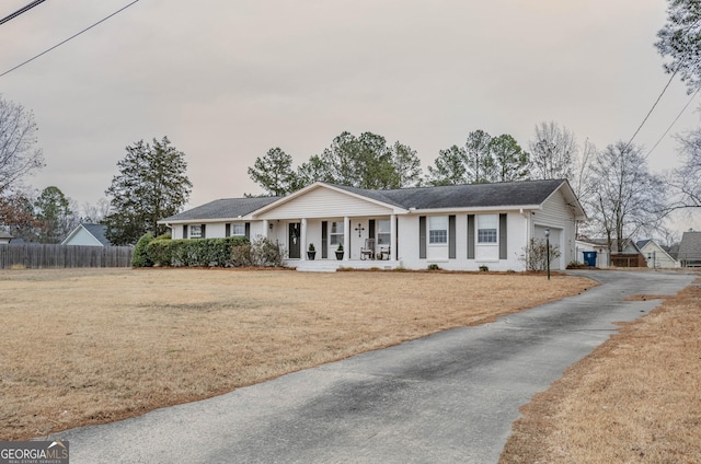 ranch-style house with covered porch, a front yard, and a garage