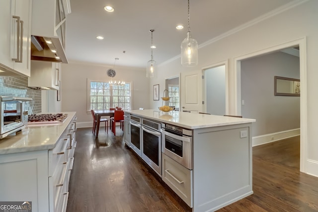 kitchen with white cabinets, a kitchen island, decorative light fixtures, stainless steel appliances, and decorative backsplash