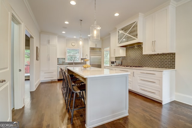 kitchen featuring pendant lighting, appliances with stainless steel finishes, a center island, white cabinetry, and backsplash