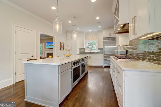 kitchen with dark hardwood / wood-style flooring, decorative light fixtures, white cabinets, a kitchen island, and stainless steel appliances