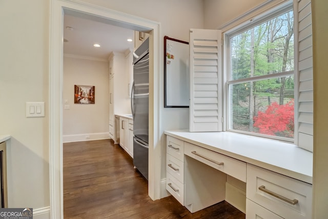 office area featuring built in desk, crown molding, and dark wood-type flooring