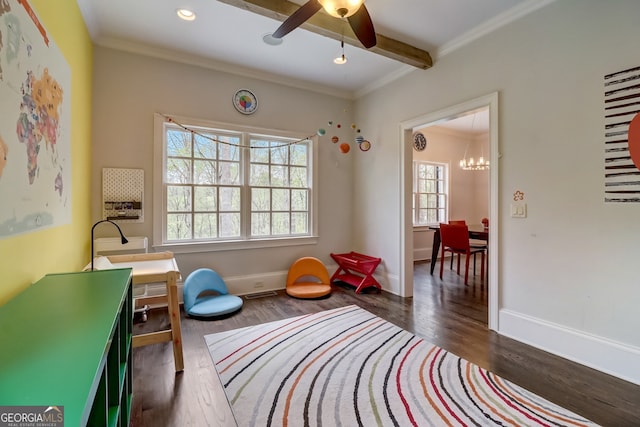 playroom featuring ceiling fan with notable chandelier, plenty of natural light, dark hardwood / wood-style flooring, and crown molding