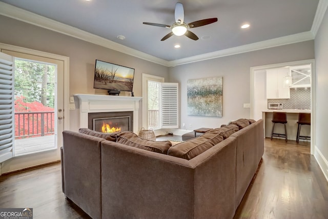 living room with light wood-type flooring, ceiling fan, and ornamental molding