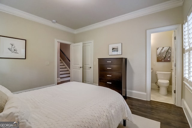 bedroom with connected bathroom, dark hardwood / wood-style floors, and ornamental molding