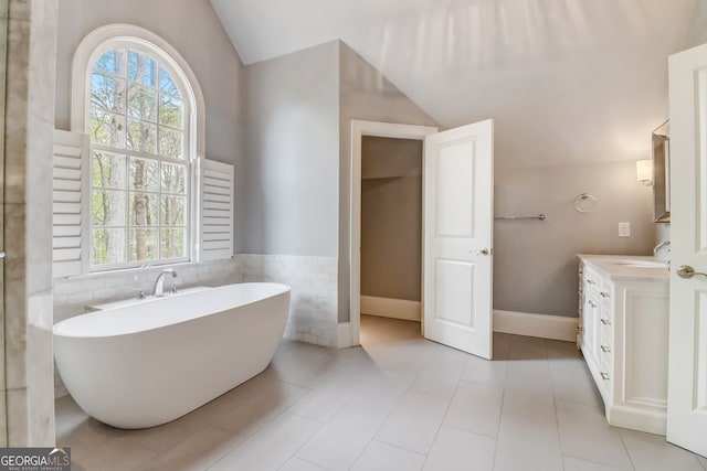 bathroom with plenty of natural light, a washtub, vanity, and lofted ceiling